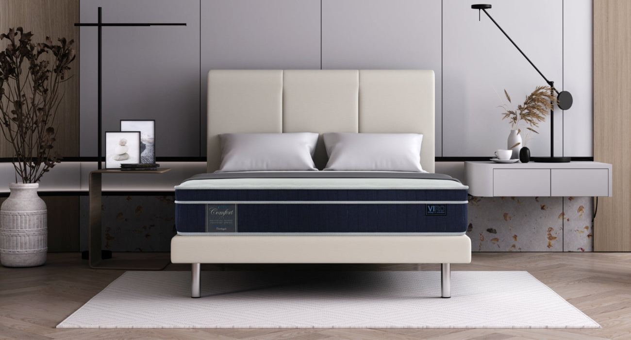 Mattress with beige upholstered bed frame in bedroom. 